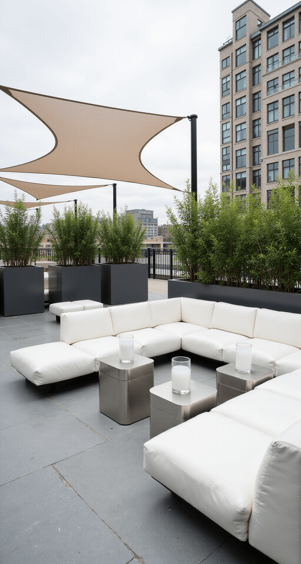 A minimalist rooftop lounge with low-profile white seating, sleek metal side tables, frosted glass containers, and a retractable shade sail casting shadows, captured from above to highlight clean lines and geometric patterns.