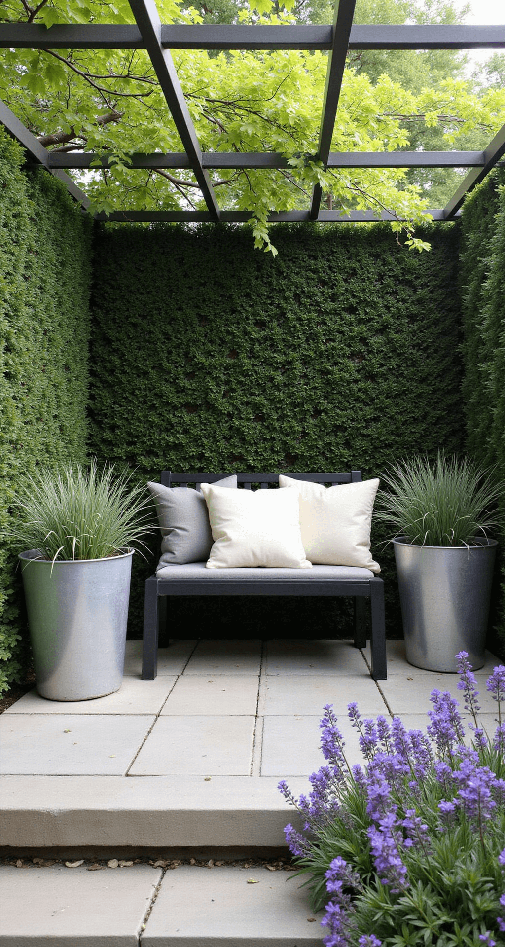 A cozy 8x8ft garden corner with a minimalist black metal bench surrounded by structured box hedging, dappled morning light filtering through a pergola, oversized zinc planters with architectural grasses, and informal drifts of purple salvias, featuring natural stone paving in warm grey tones and simple cream linen cushions.