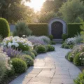 A photorealistic image of a modern cottage garden at golden hour, featuring a winding slate pathway, silvery lamb's ear, white cosmos flowers, blush pink David Austin roses, purple lavender, white hydrangea, and black metal archway, with a soft pastel color palette and natural bokeh effect.