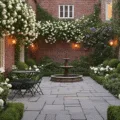 A photorealistic wide-angle view of an intimate English courtyard garden at golden hour, showcasing weathered brick walls adorned with white roses and ivy, a geometric stone-paved ground, a green bistro set, and vibrant hydrangeas and clematis in bloom, highlighted by warm copper lanterns and a central antique fountain, all captured from an elevated perspective in 8K resolution.