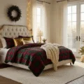 A luxurious master bedroom decorated for Christmas at golden hour, featuring a king-sized bed with a plaid quilt, Christmas tree with vintage ornaments, herringbone hardwood floors, and festive garland.