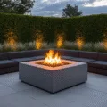 Photorealistic image of a modern square concrete fire pit surrounded by charcoal sectional seating in a minimalist backyard at twilight, with warm flames and subtle smoke creating a cozy atmosphere, illuminated by architectural LED uplighting against geometric hedges and silver grass.