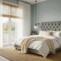 Photorealistic interior of a luxurious bedroom with golden hour sunlight, featuring a tufted grey velvet headboard, crisp white linens layered with cream and taupe textiles, vintage brass lamps, a natural jute rug, and woven bamboo blinds, shot from a doorway perspective with shallow depth of field.