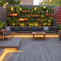A photorealistic urban deck at golden hour featuring herringbone-patterned gray composite decking, an L-shaped bench with charcoal cushions, and a vertical garden wall with copper planters. The scene is illuminated by warm string lights, modern minimalist furniture, and a Japanese maple in a contemporary planter, creating a cozy outdoor retreat.