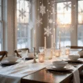 Elegant winter wonderland dining room featuring a shimmering white silk table runner, cascading snowflakes, mercury glass candleholders, and illuminated branches, all captured in soft natural light.
